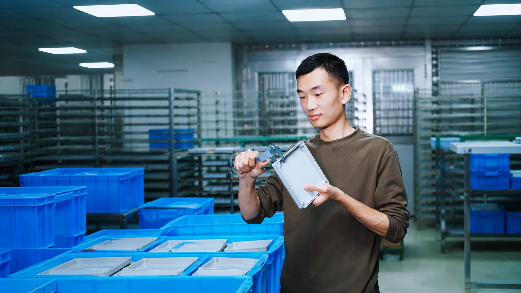 Worker checking waterproof enclosure dimensions with a caliper